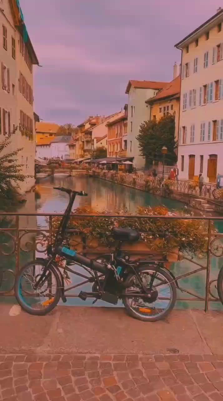 This may contain: a bicycle parked next to a railing in front of some buildings on the other side