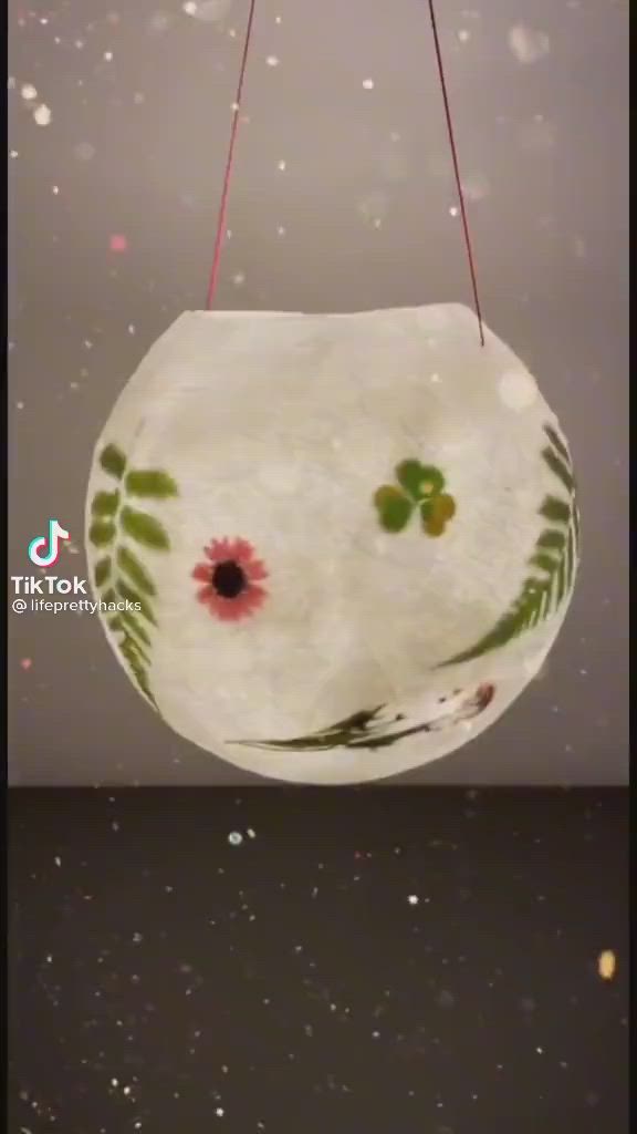 This may contain: a glass ball with flowers and leaves painted on it sitting on top of a table