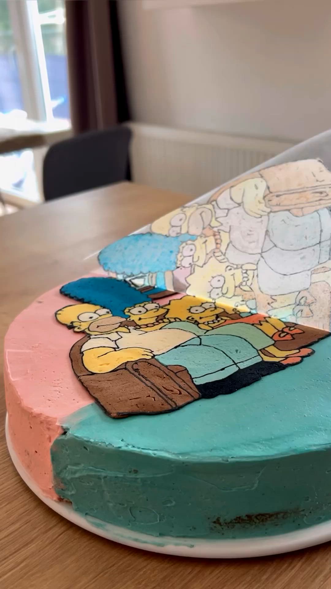 This may contain: a cake decorated with cartoon characters on top of a wooden table in front of a window