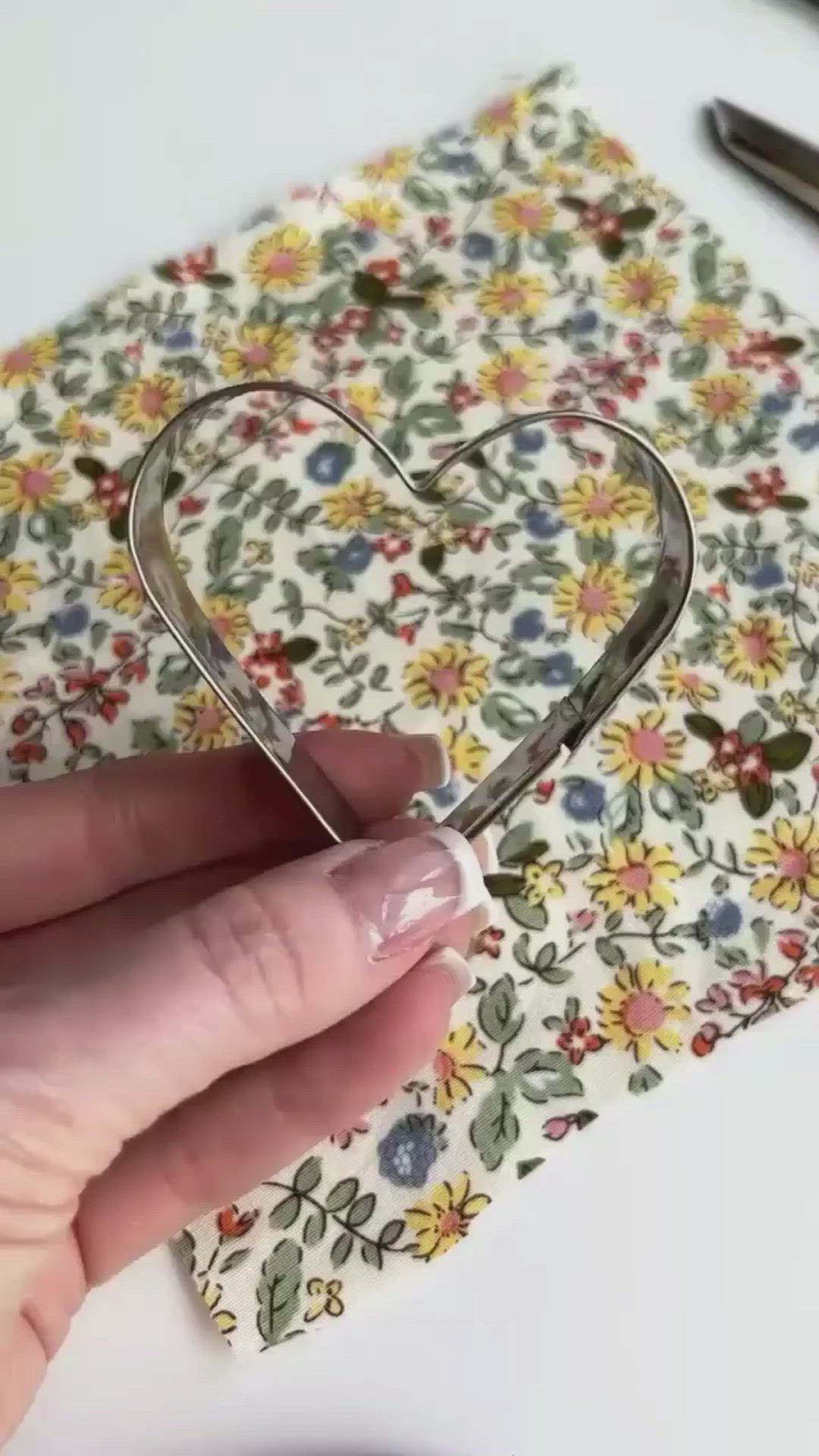 This may contain: someone is cutting out a heart shaped paper piece with scissors and some other crafting supplies