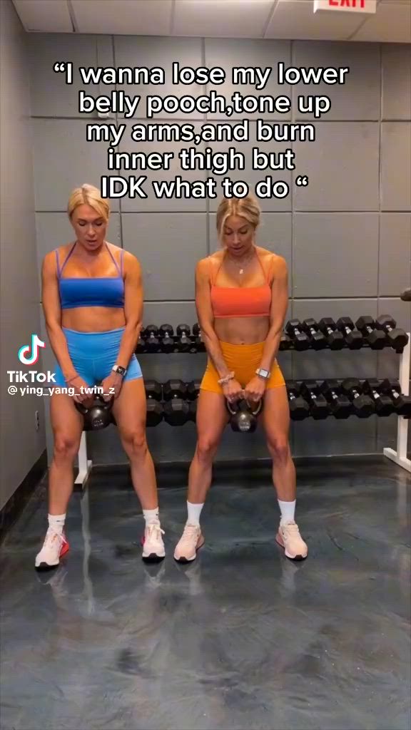This may contain: two women in sports bras and shorts sitting on a bench with dumbbells