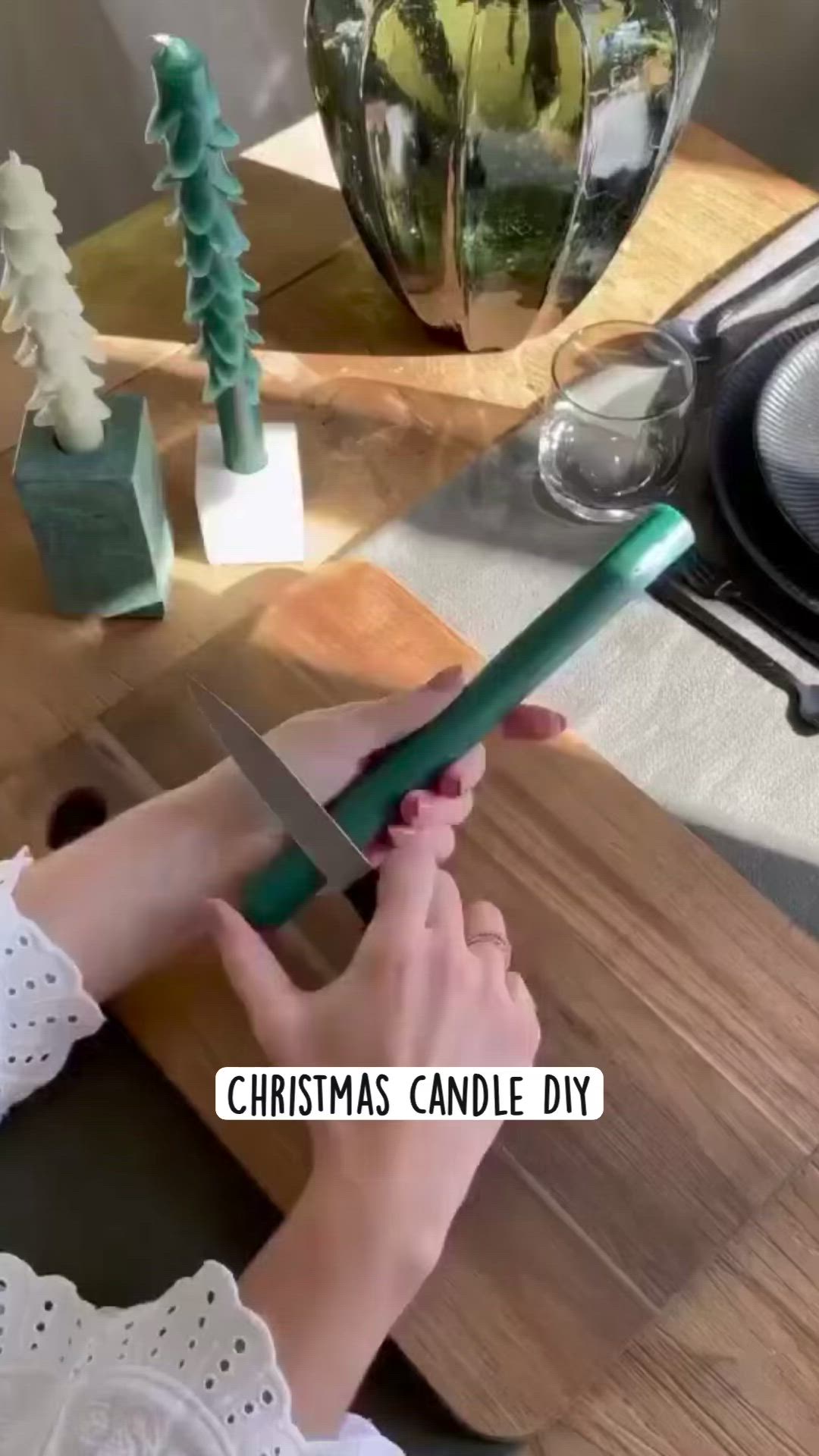 This may contain: a woman is holding a knife on a table with christmas decorations in the background and text overlay that reads, christmas candle diy