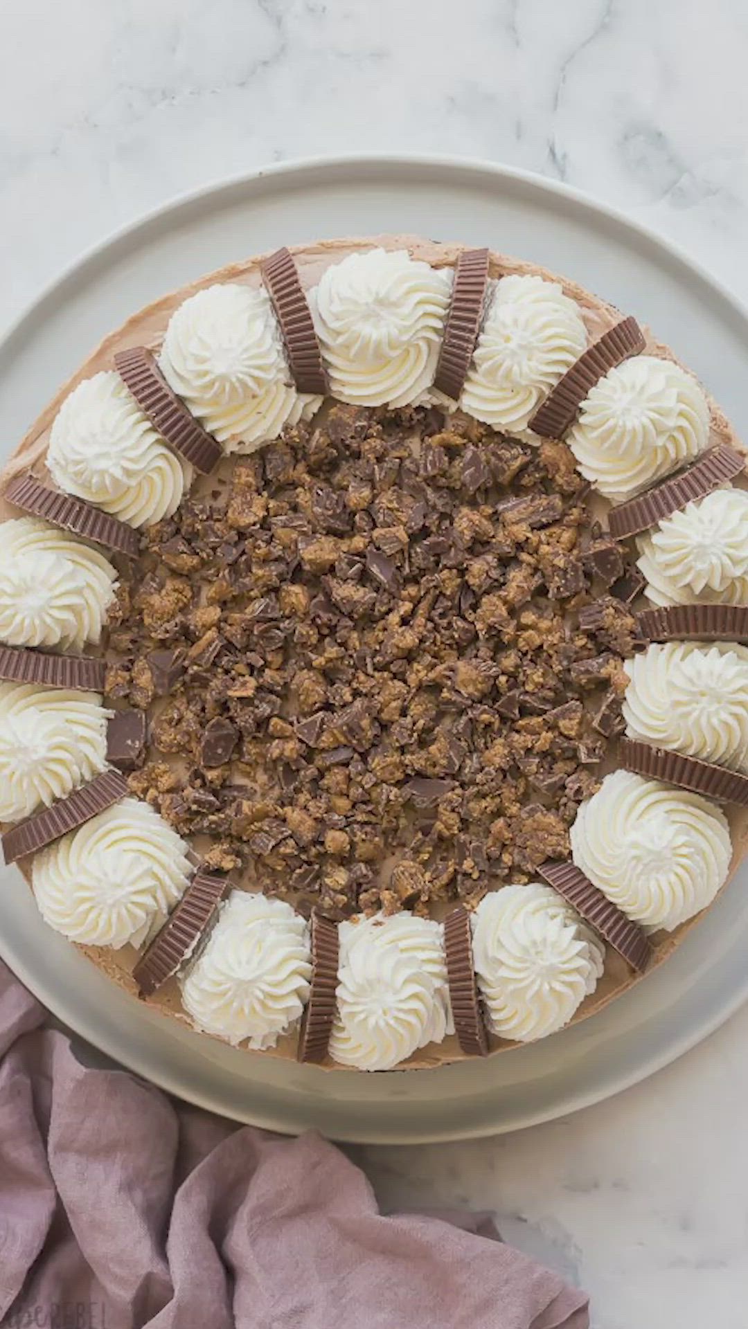 This may contain: a cake on a plate with white frosting and chocolate pieces in the top layer