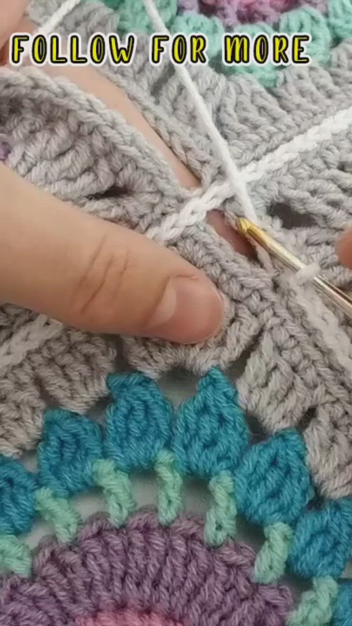 This may contain: someone crocheting on the side of a blanket with yarn