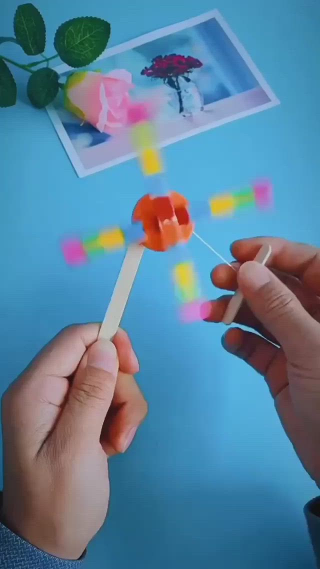 This may contain: a person is spinning an orange object on a blue surface with flowers in the background