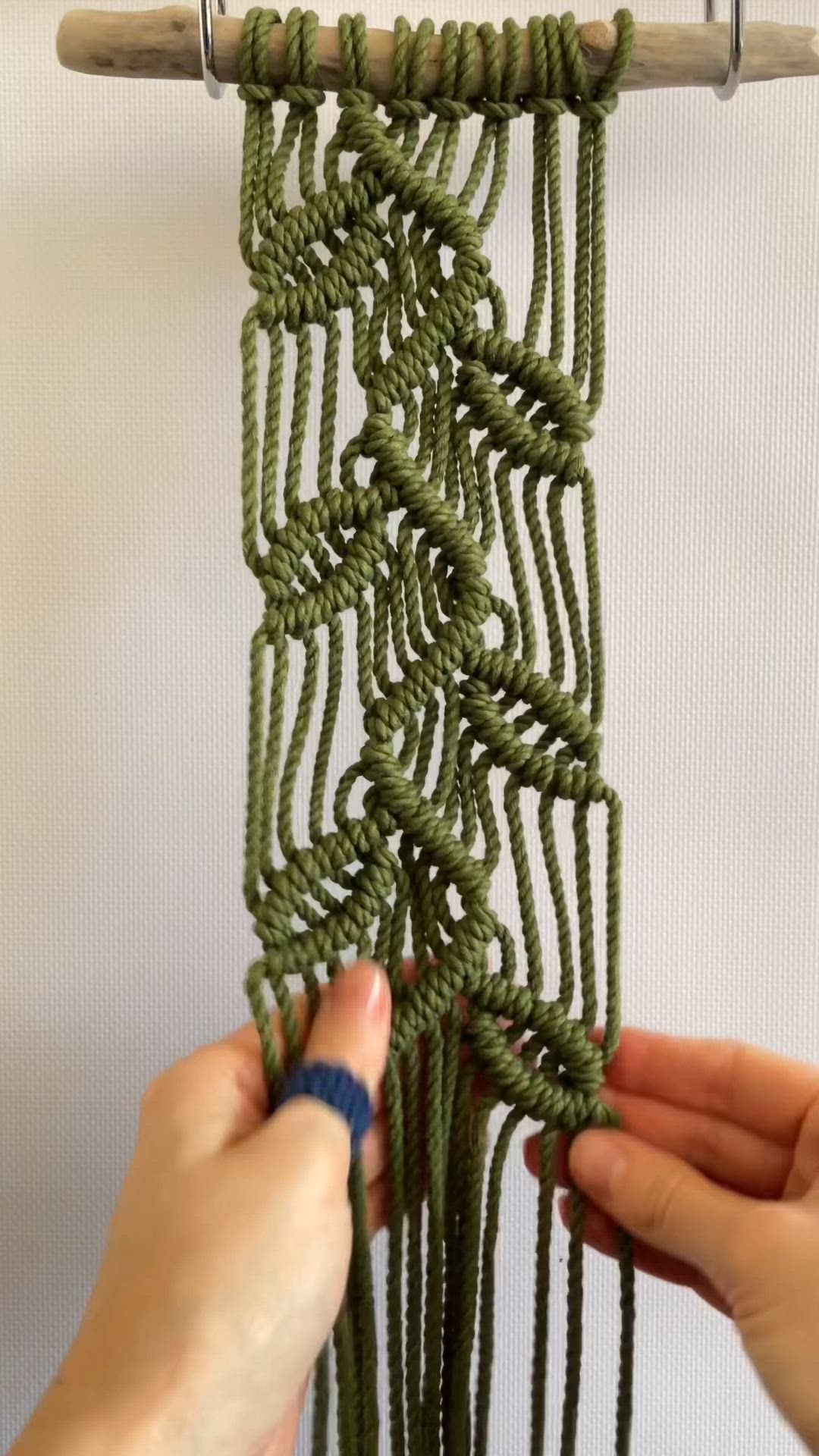 This may contain: two hands are working on a piece of green string art that is hanging from a wall