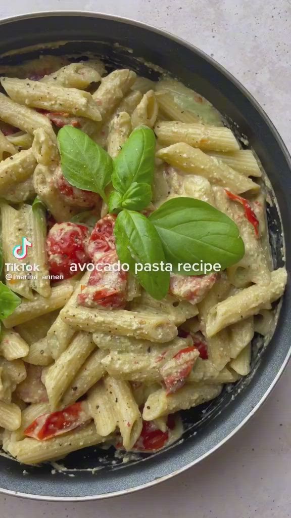 This may contain: pasta with pesto and tomatoes in a pan