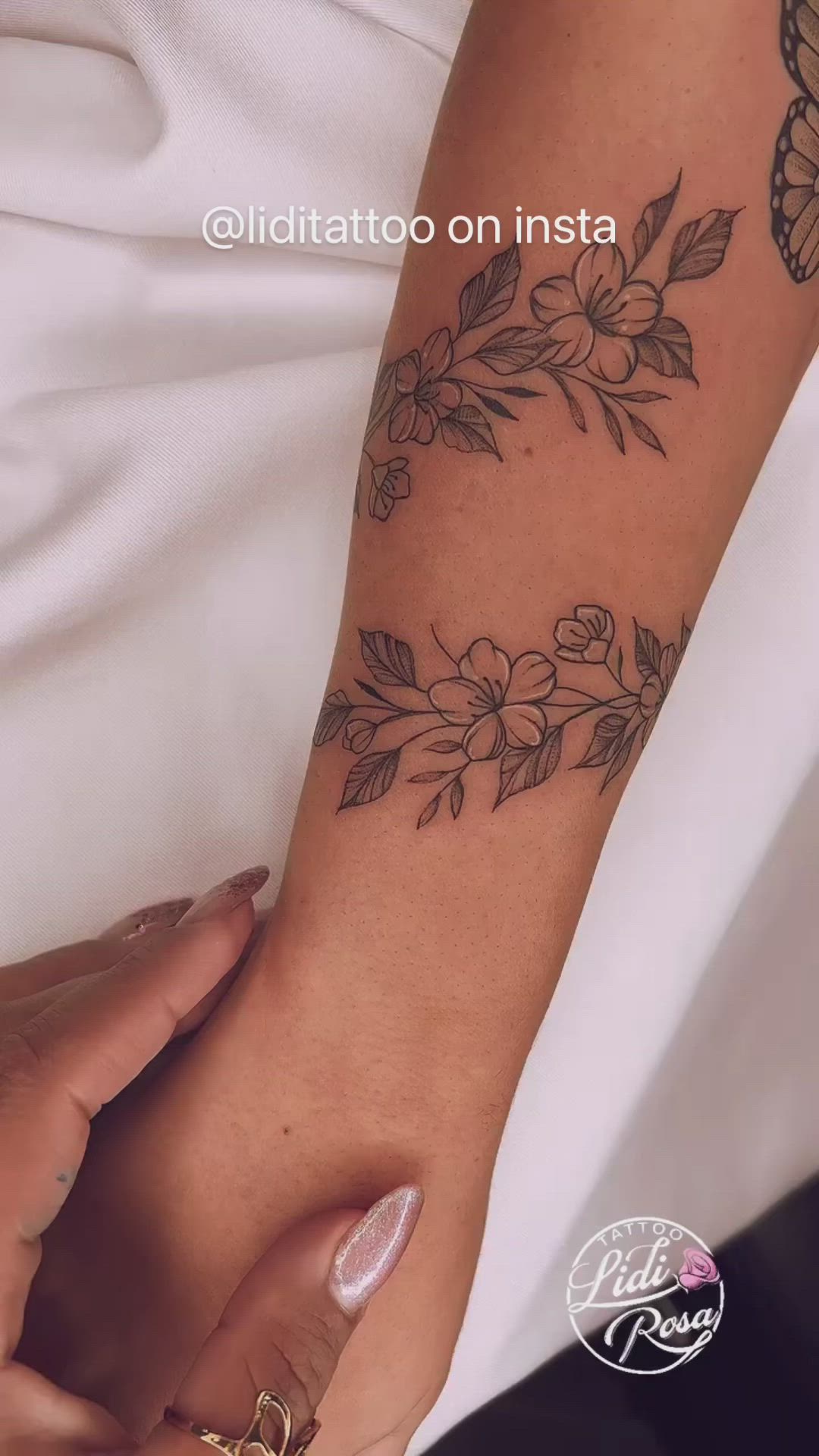 This may contain: a woman's arm with flowers on it and butterflies around the wrist tattoo design