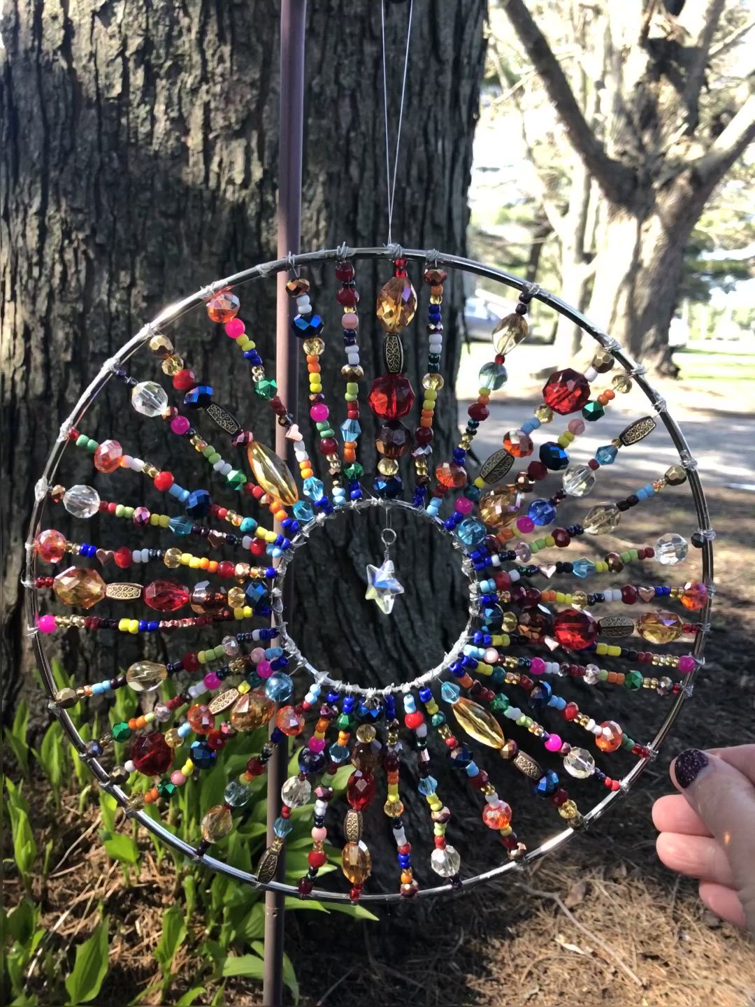 This may contain: a wind chime hanging from a tree in front of a tree with lots of beads on it