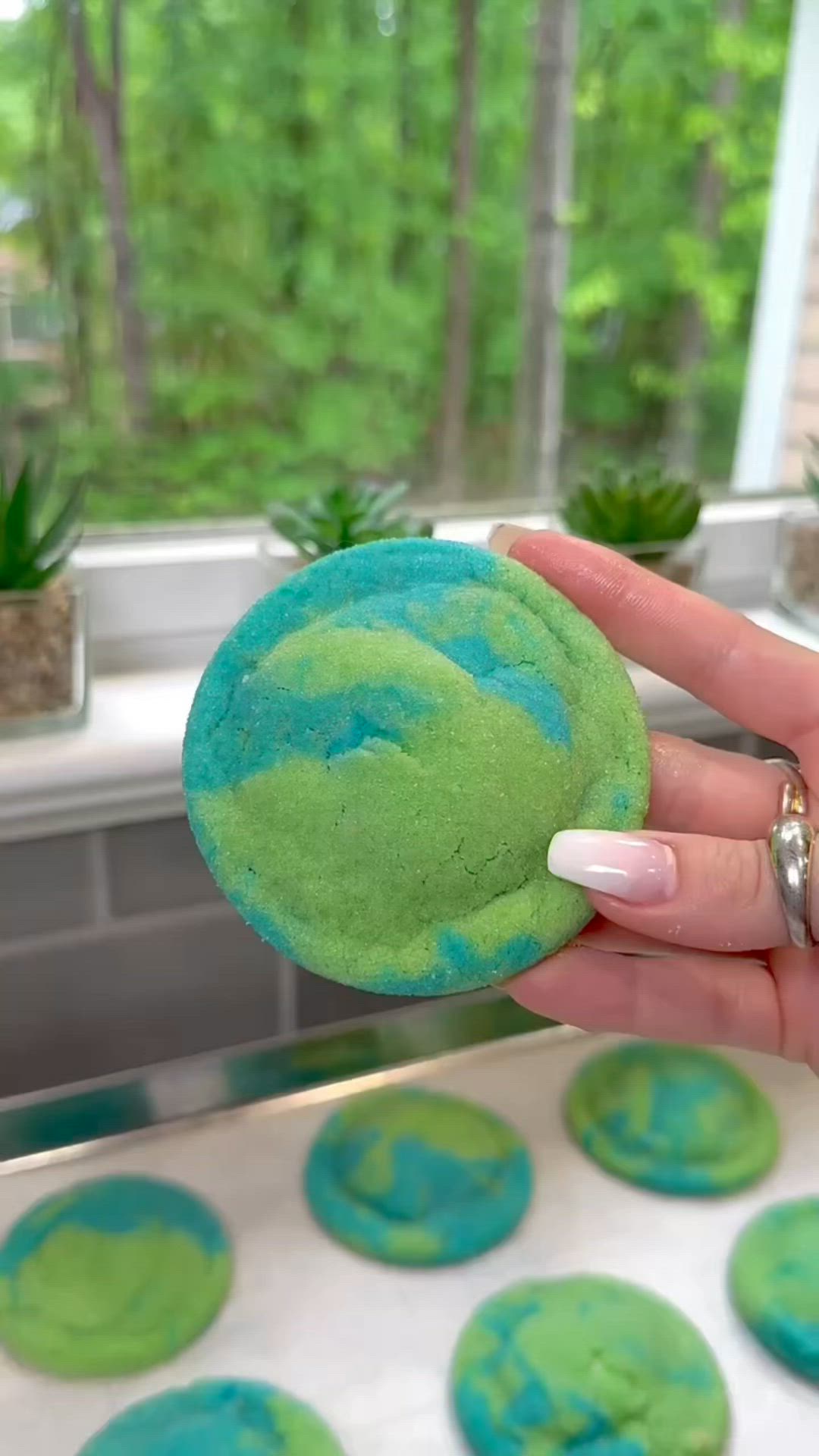 This may contain: a hand holding a green and blue cookie