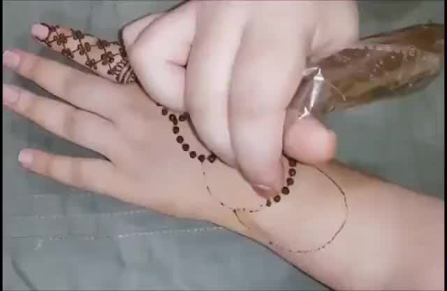 This may contain: a woman's hands with henna tattoos on her arm and hand holding something in the other hand