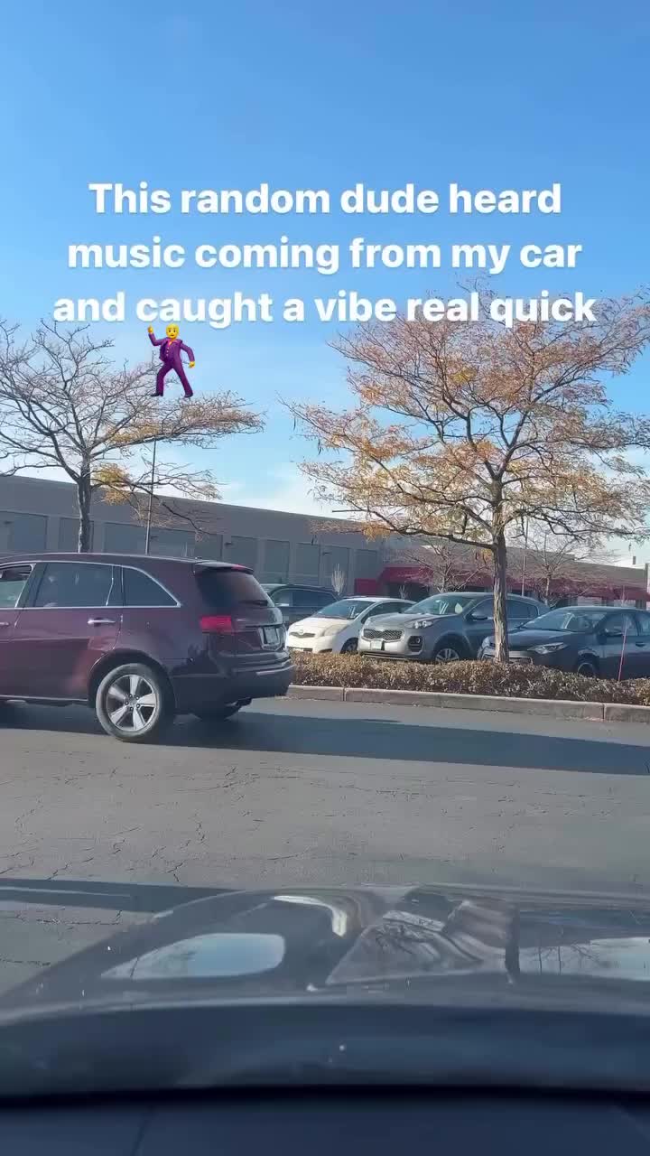 This may contain: a person jumping in the air over a parking lot with cars parked on both sides