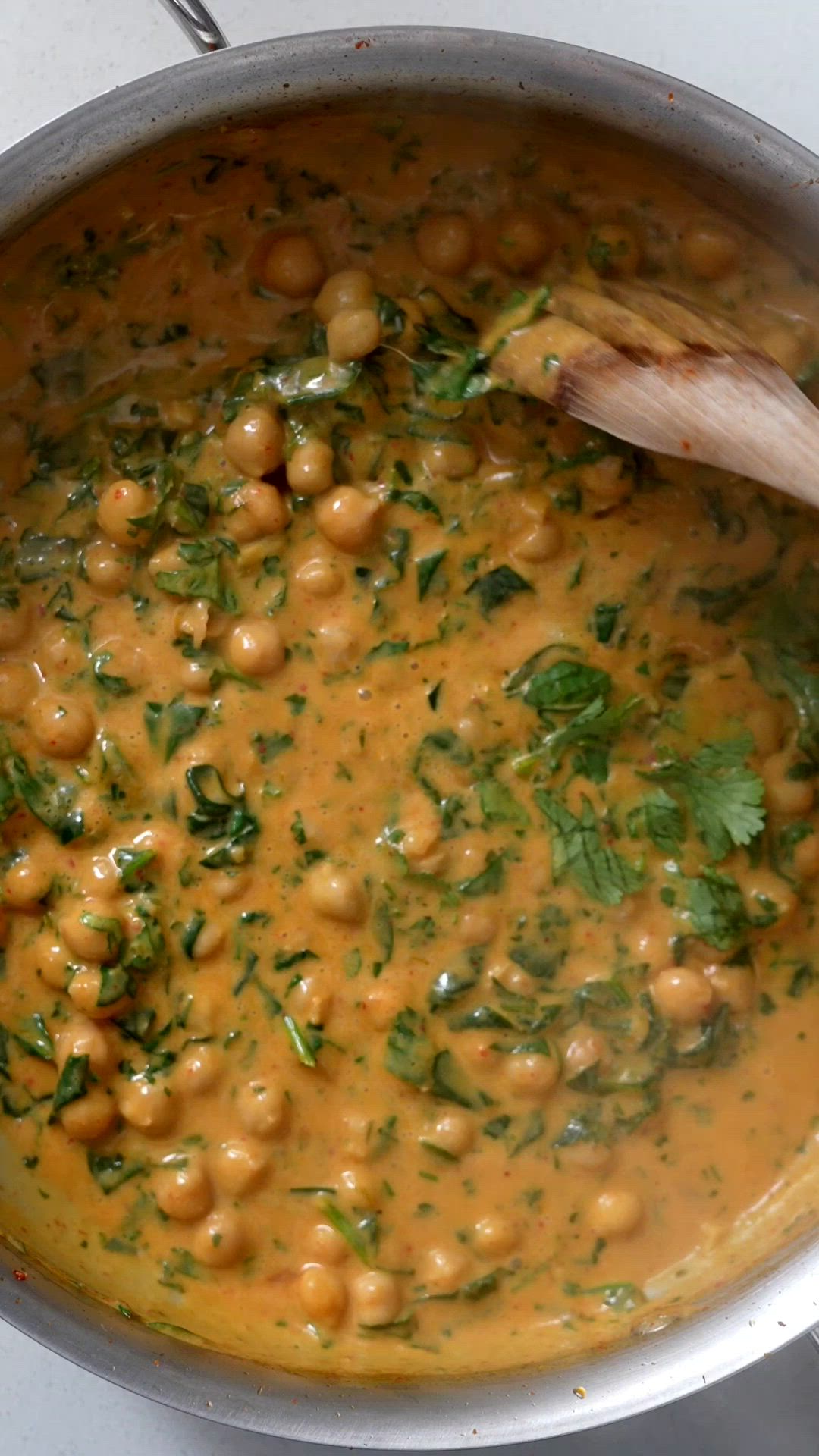 This contains: Making an easy coconut curry sauce in a pan, then adding chickpeas and spinach. The curry is piled on top of rice with a spoonful of chili crisp.