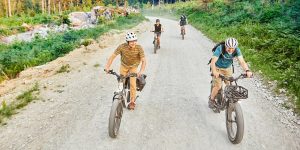 a group of people riding bikes on a dirt road