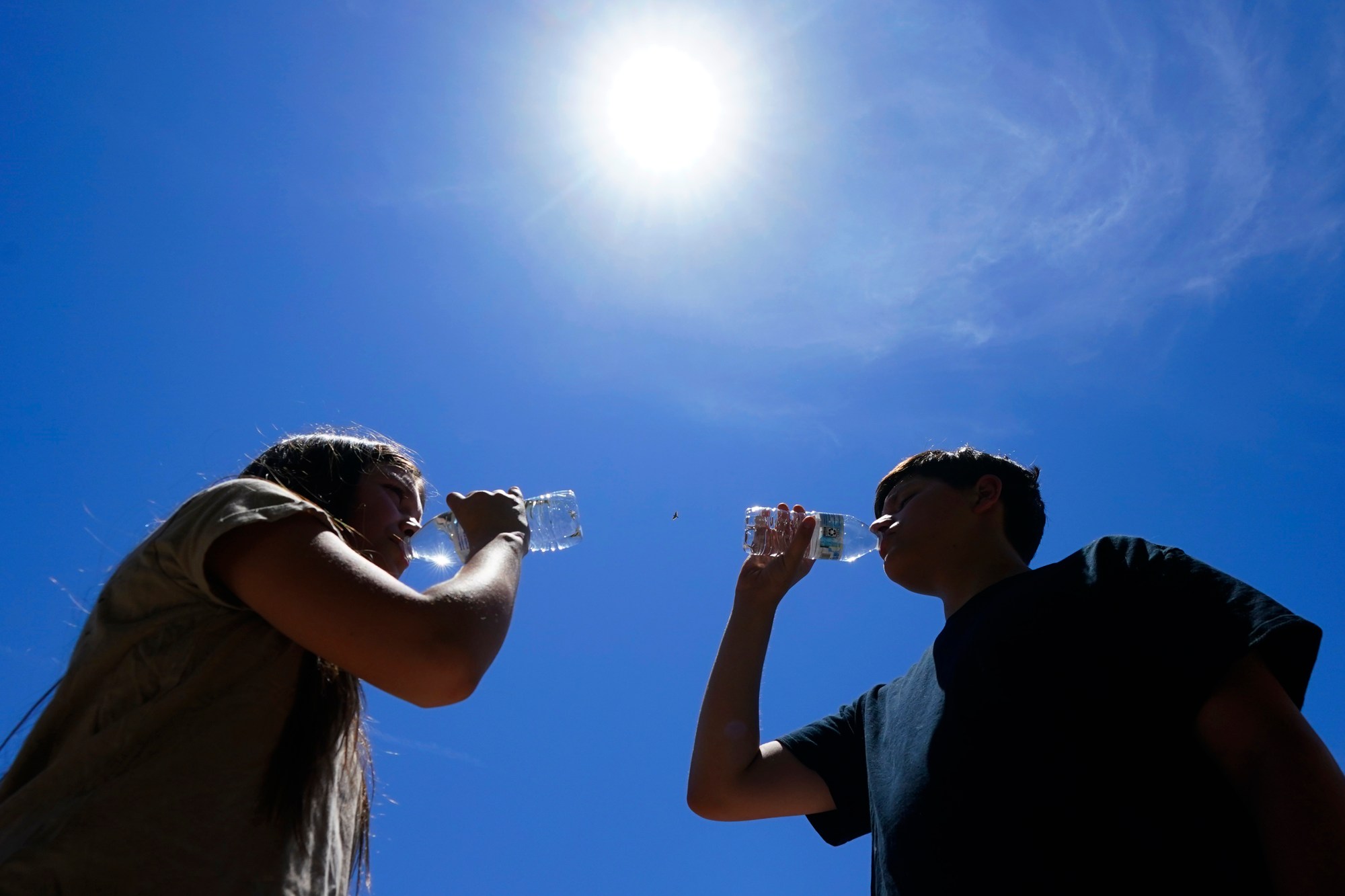 FILE - Tony Berastegui Jr., right, and his sister Giselle Berastegui drink water, Monday, July 17, 2023, in Phoenix. A historic heat wave that turned the Southwest into a blast furnace throughout July is beginning to abate with the late arrival of the monsoon rains. Forecasters expect that by Monday, July 31, at the latest, people in metro Phoenix will begin seeing high temperatures under 110 degrees Fahrenheit (43.3 degrees Celsius) for the first time in a month. (AP Photo/Ross D. Franklin, File)