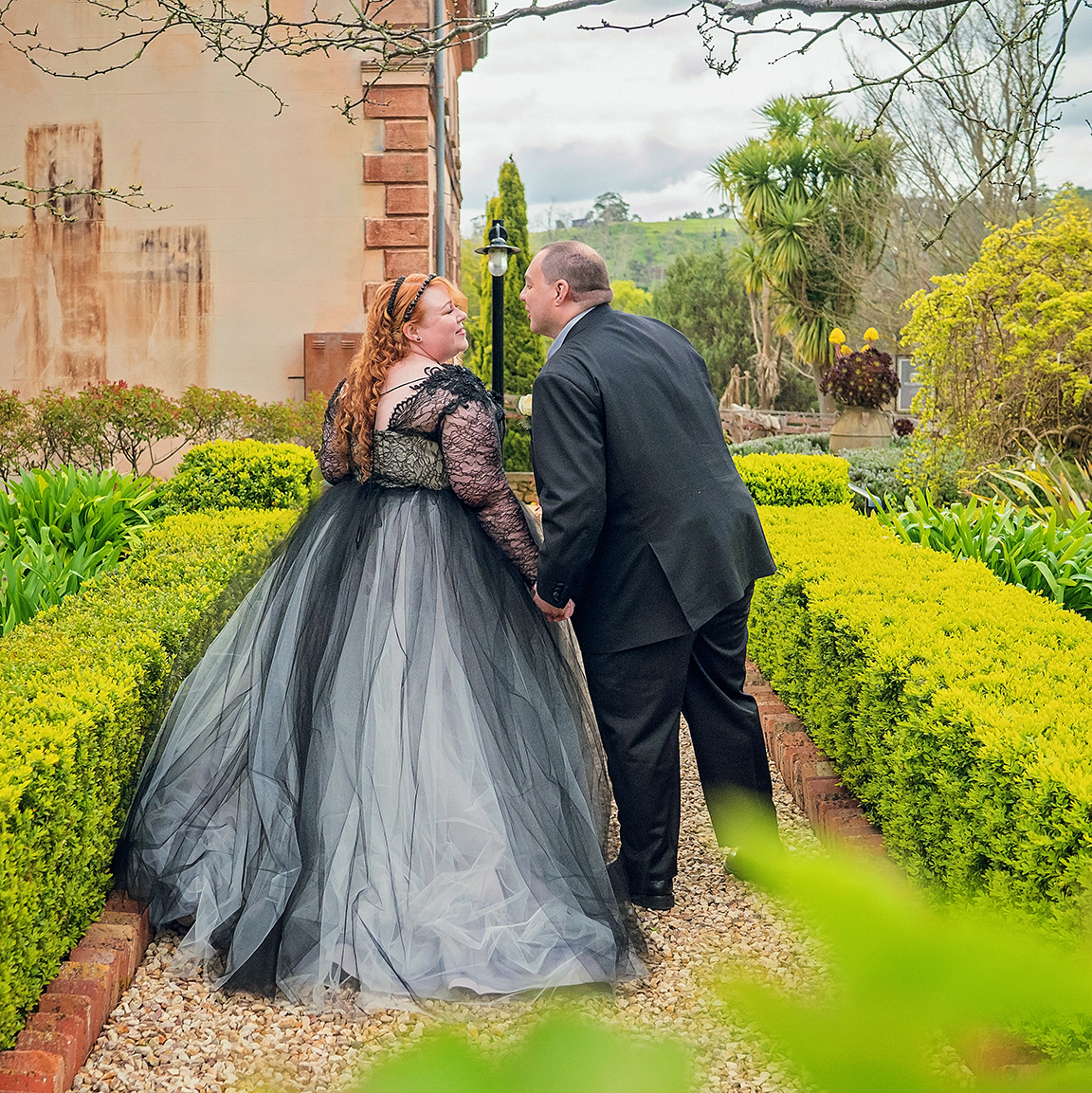 plus size bride and groom walking in formal tuscan style garden