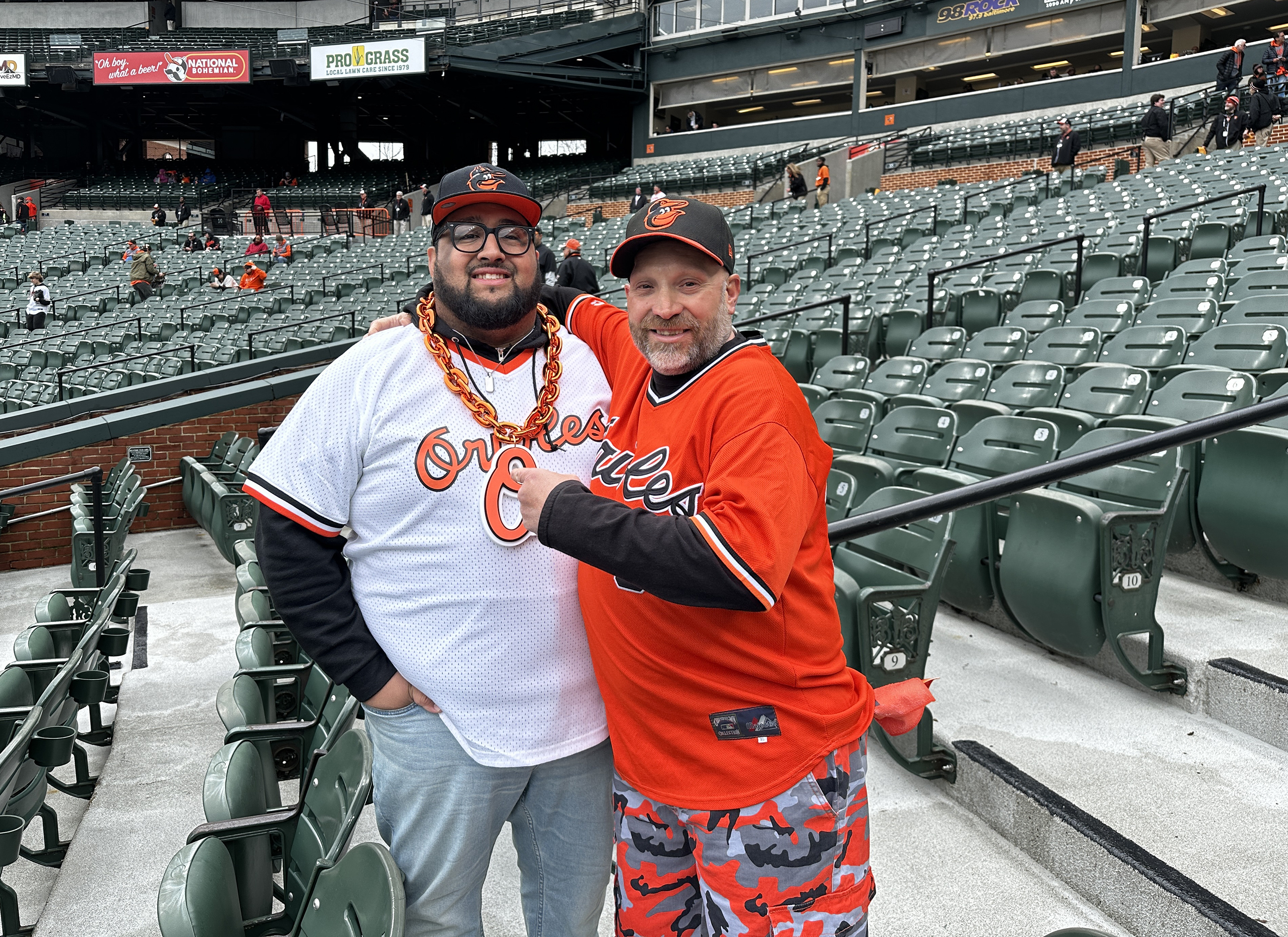 March 28, 2024: Sebastian Tirado, left, and Will Rice, right, take in batting practice before opening day. Rice remembers being at the first Camden Yards opening day back in 1992, soaking in the new beginnings of 32 years ago. (Sam Cohn/Staff)