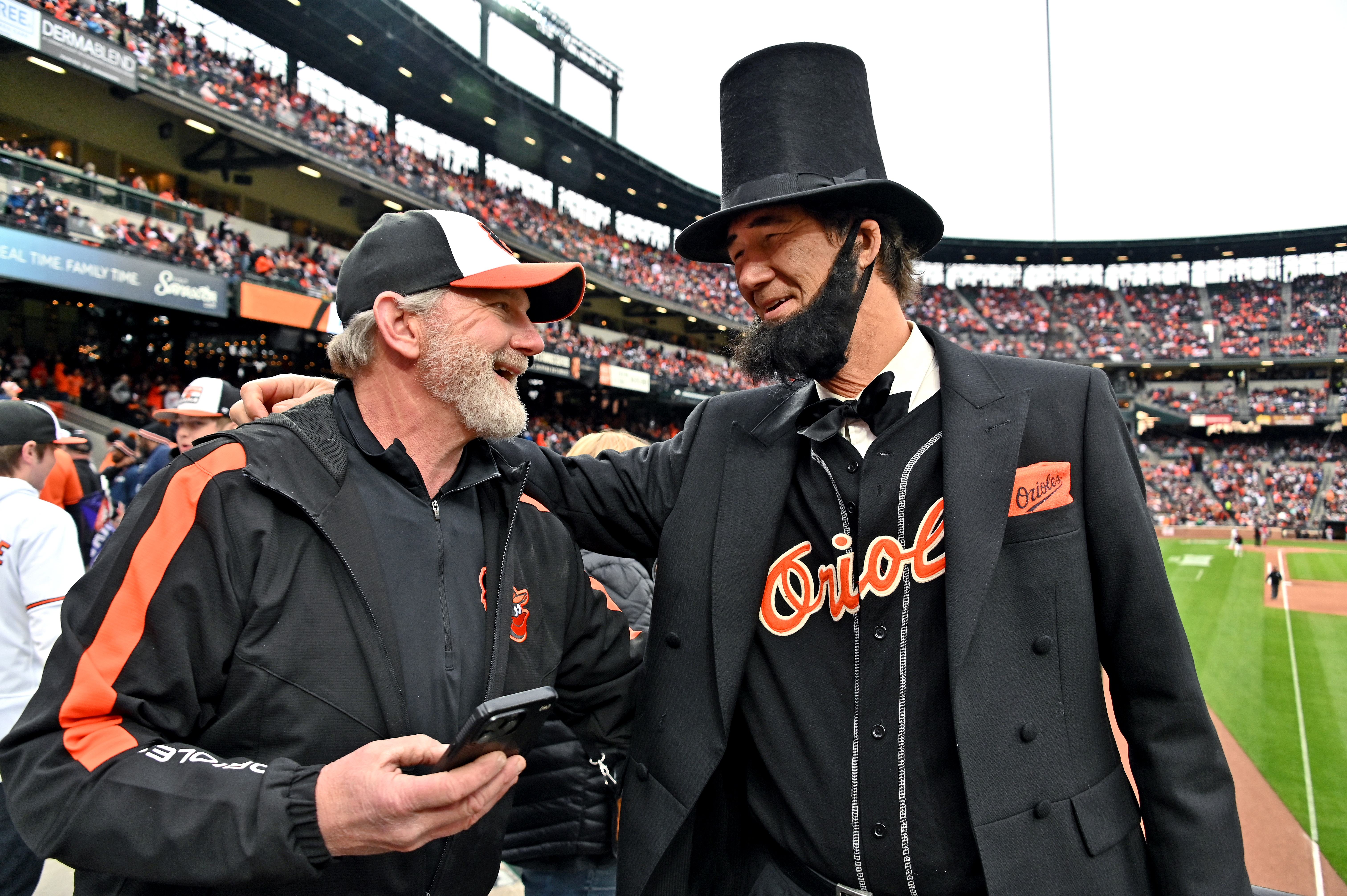 Mar. 28, 2024: Ray Price, of Kennedyville, shares a smile with Abe Lincoln presenter Duke Thompson, of Havre de Grace, after taking a selfie on opening day. The Baltimore Orioles host the Los Angeles Angels at Oriole Park at Camden Yards. (Kim Hairston/Staff)