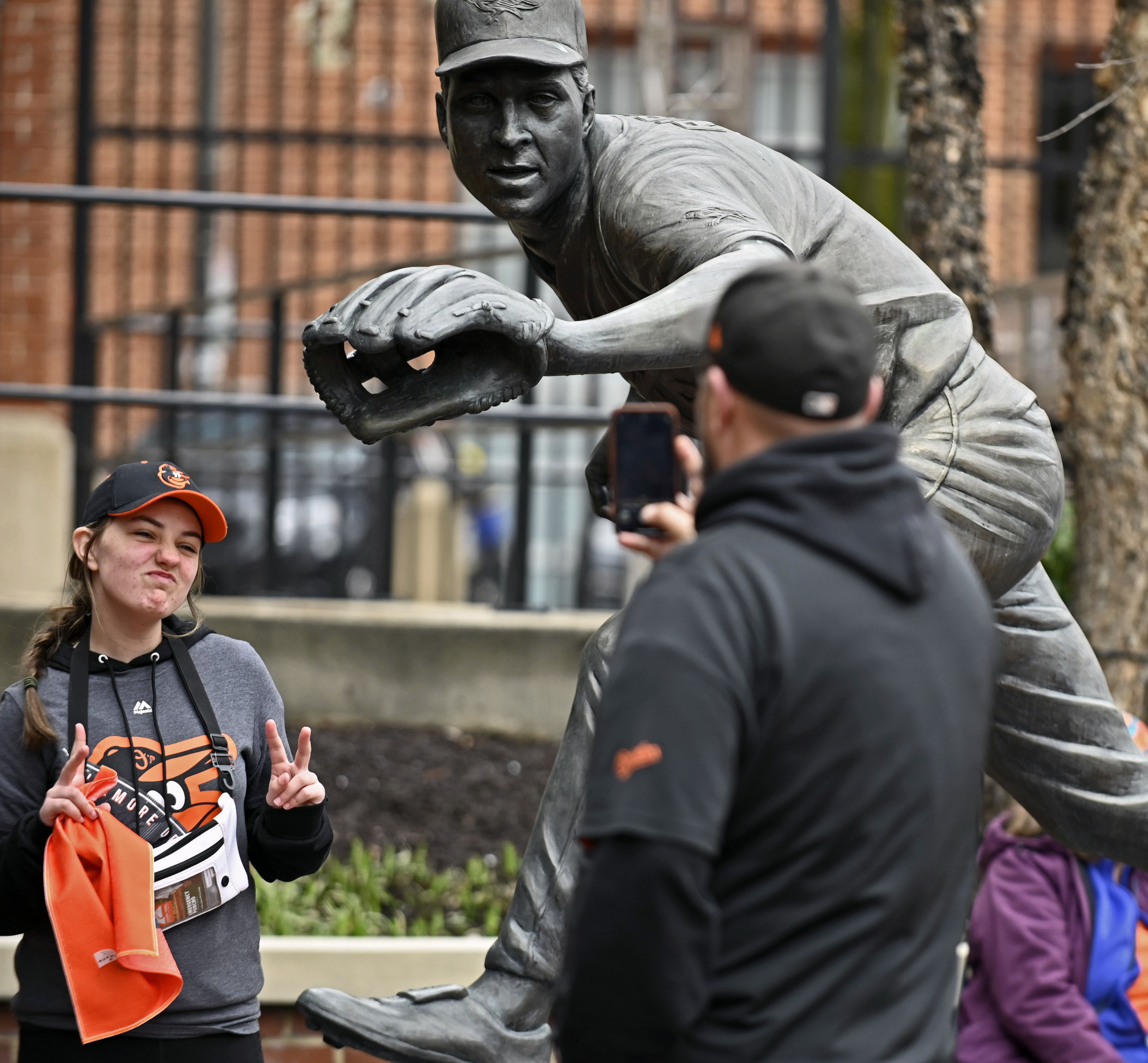 Mar 28, 2024: Rob Meissner, right, of Preston, Md., takes pictures of daughter Evan, 12, with Cal Ripken Jr.'s statue during Orioles 2024 season opening day at Oriole Park at Camden Yards. Ripken is part of the new ownership of the Orioles. (Kenneth K. Lam/Staff)