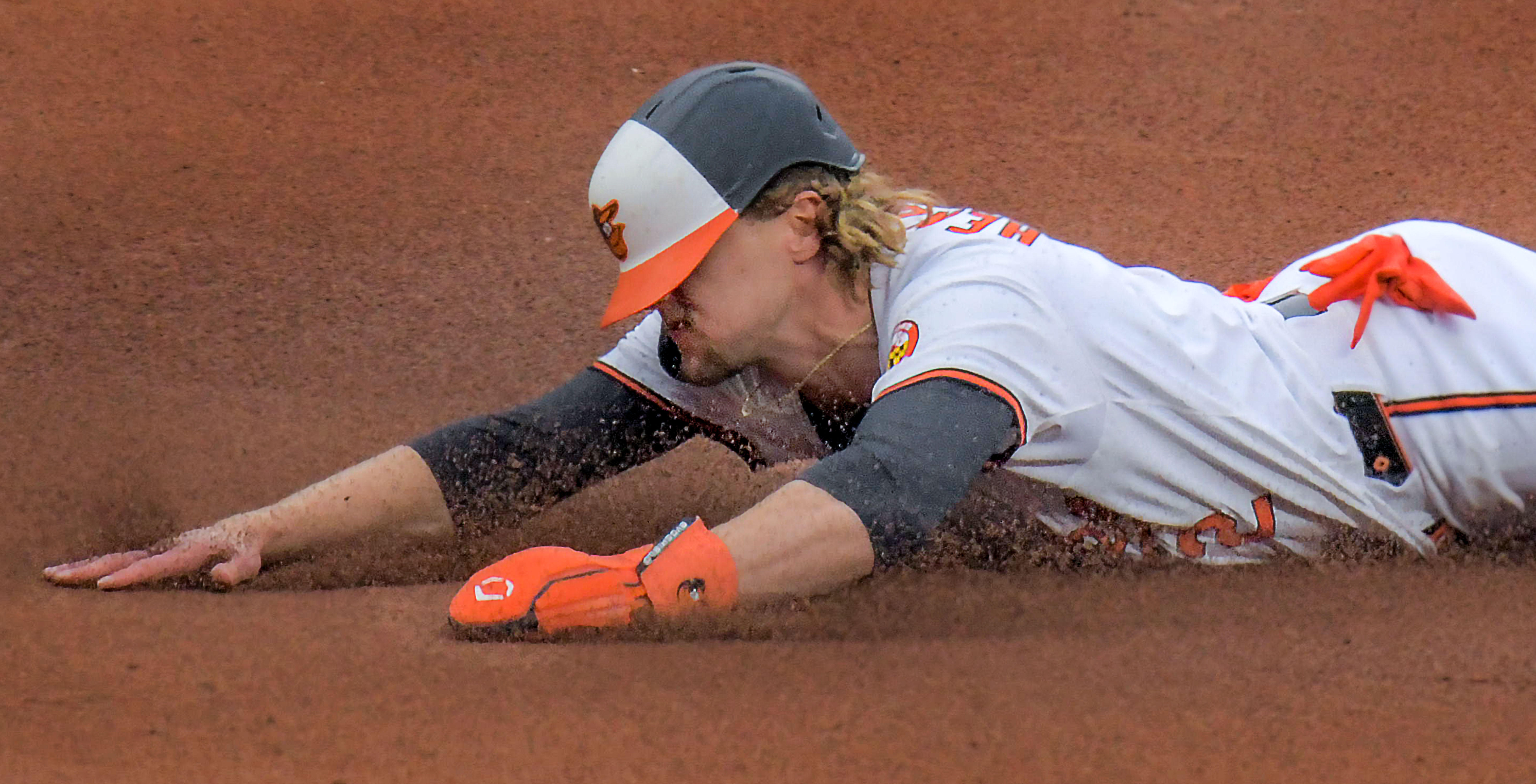 Mar 28, 2024: Baltimore Orioles' Gunnar Henderson gets dirty, bellyflopping into third base on a single from batter Adley Rutschman in the first inning during opening day of Major League Baseball at Oriole Park at Camden Yards. (Karl Merton Ferron/Staff)