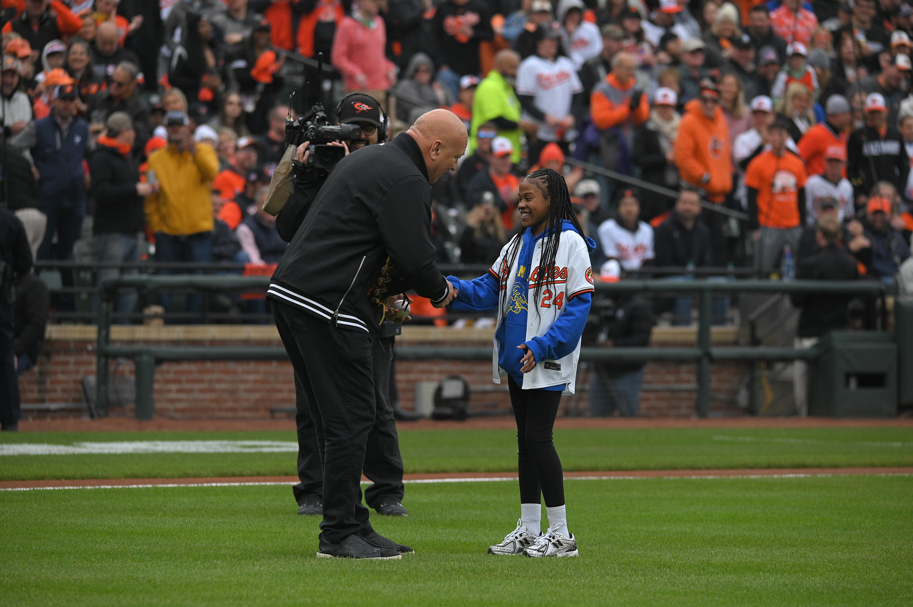 March 28, 2024: Former Orioles player Cal Ripken Jr. joins Aubree Singletary, who threw out the ceremonial first pitch, on the field during opening day ceremonies at Oriole Park at Camden Yards. (Kenneth K. Lam/Staff)