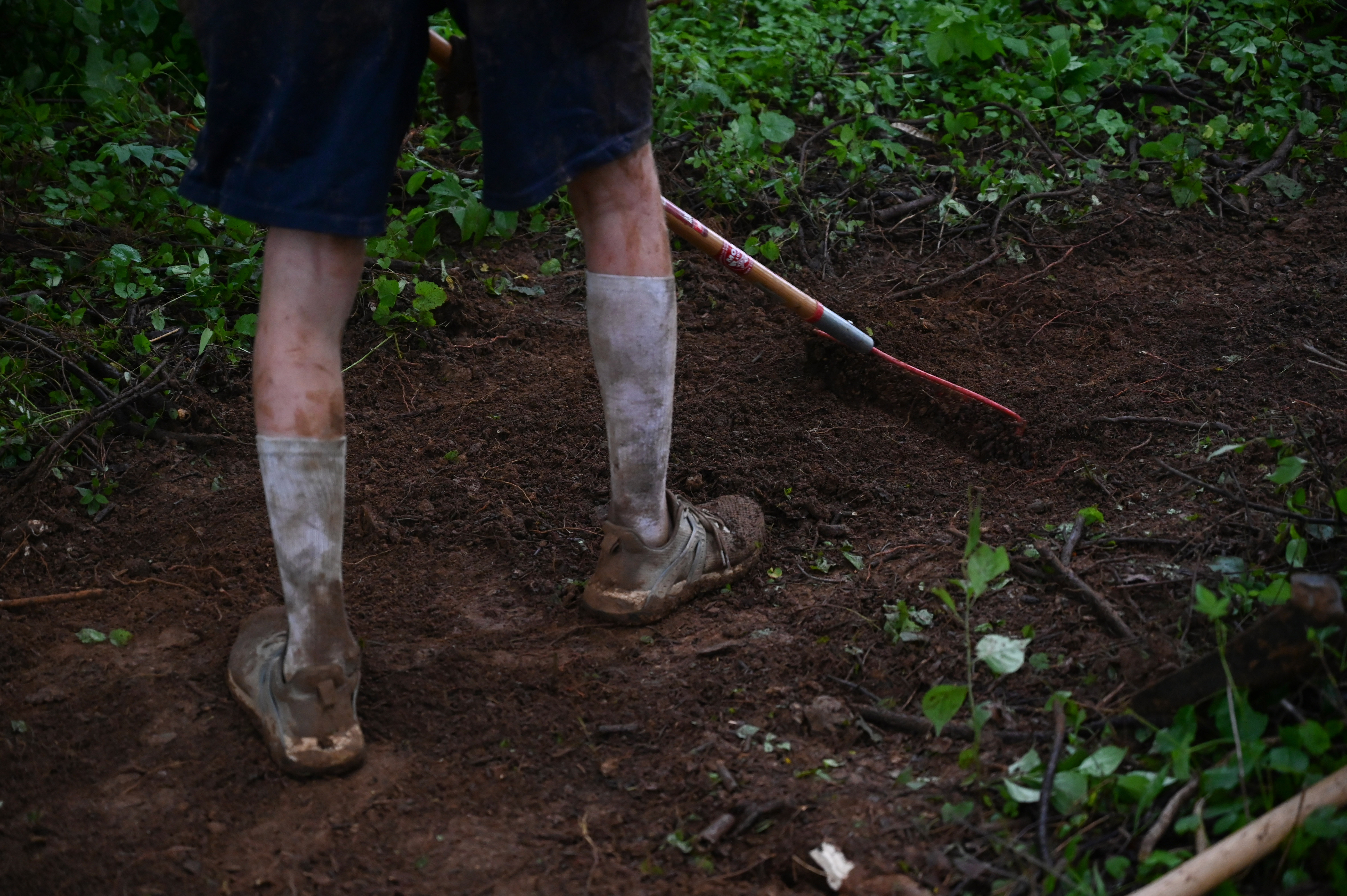 Drew Jarvis-Weaver works on clearing the path with a rake as a group of volunteers make progress in the creation of a new bike trail, Windy Ridge Trails, at Mount Airy's East West Park on Saturday. (Brian Krista/staff photo)