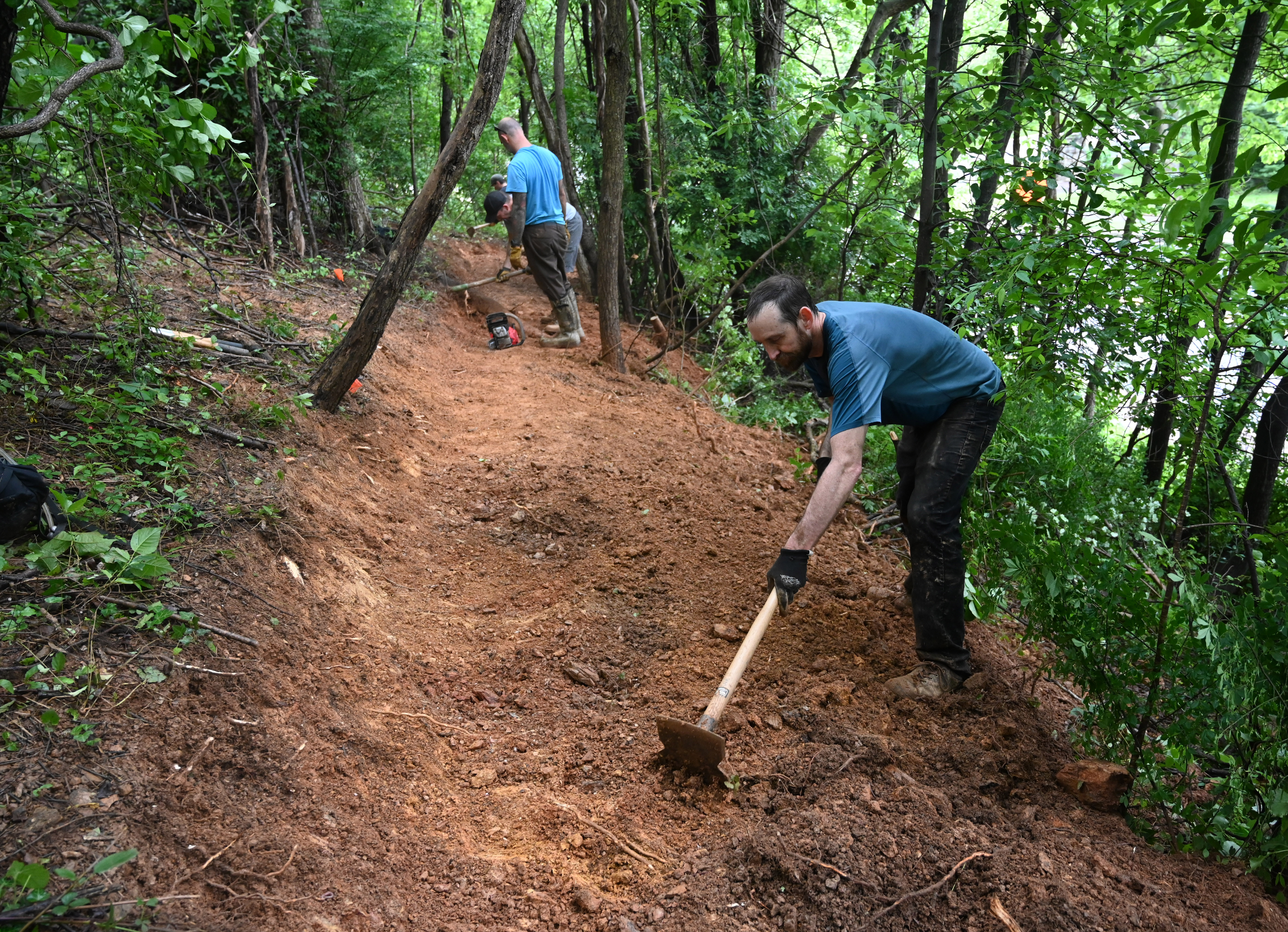 Jon Arnold works with a group of volunteers as they make progress in the creation of a new bike trail, Windy Ridge Trails, at Mount Airy's East West Park on Saturday. (Brian Krista/staff photo)