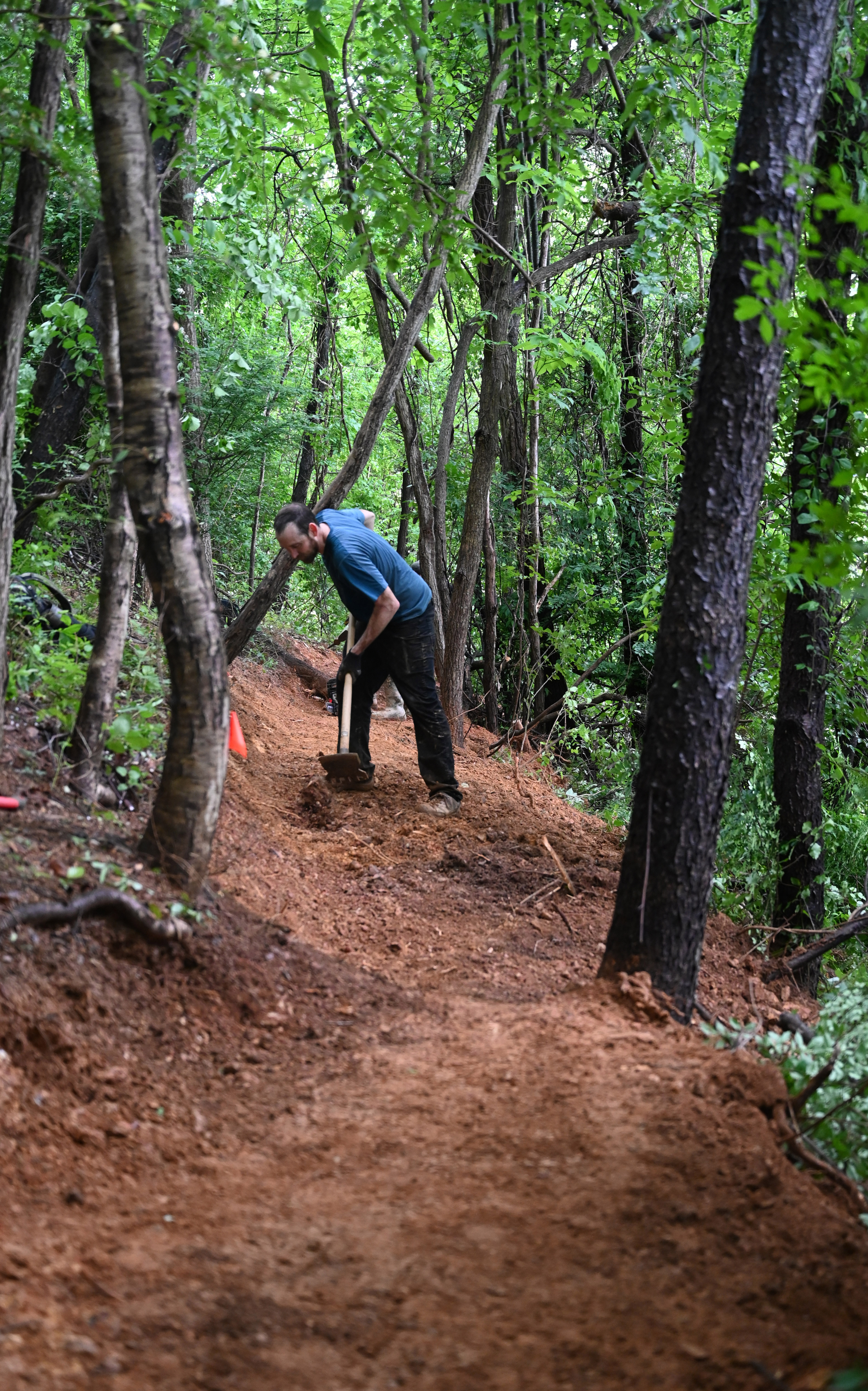 Jon Arnold works with a group of volunteers as they make progress in the creation of a new bike trail, Windy Ridge Trails, at Mount Airy's East West Park on Saturday. (Brian Krista/staff photo)