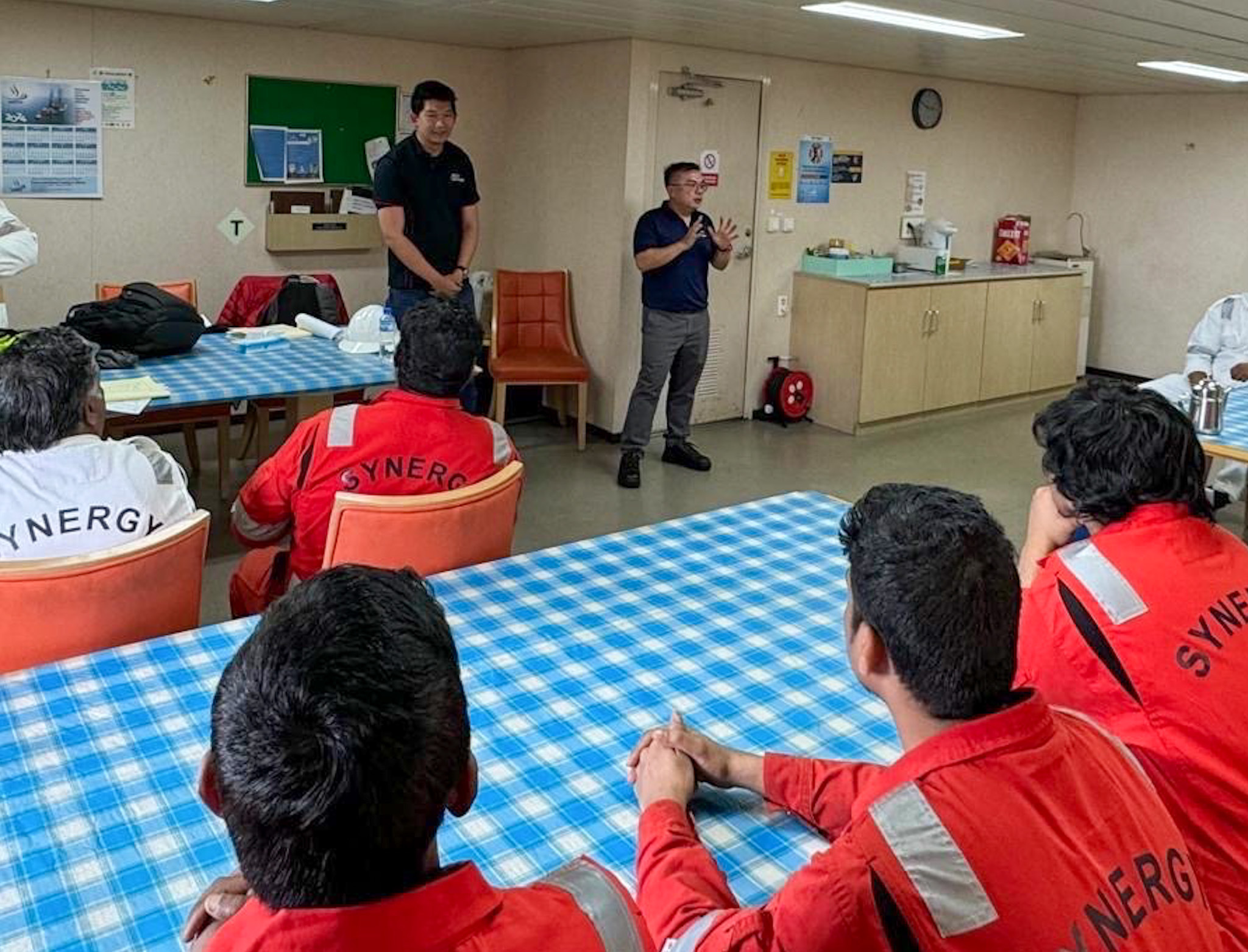 Chen Chuanyi of the Singapore Organisation of Seamen, left, in dark shirt, and Gwee Guo Duan, right, of the Singapore Maritime Officers' Union, speak to members of the crew aboard the Dali on April 24, 2024, in Baltimore.