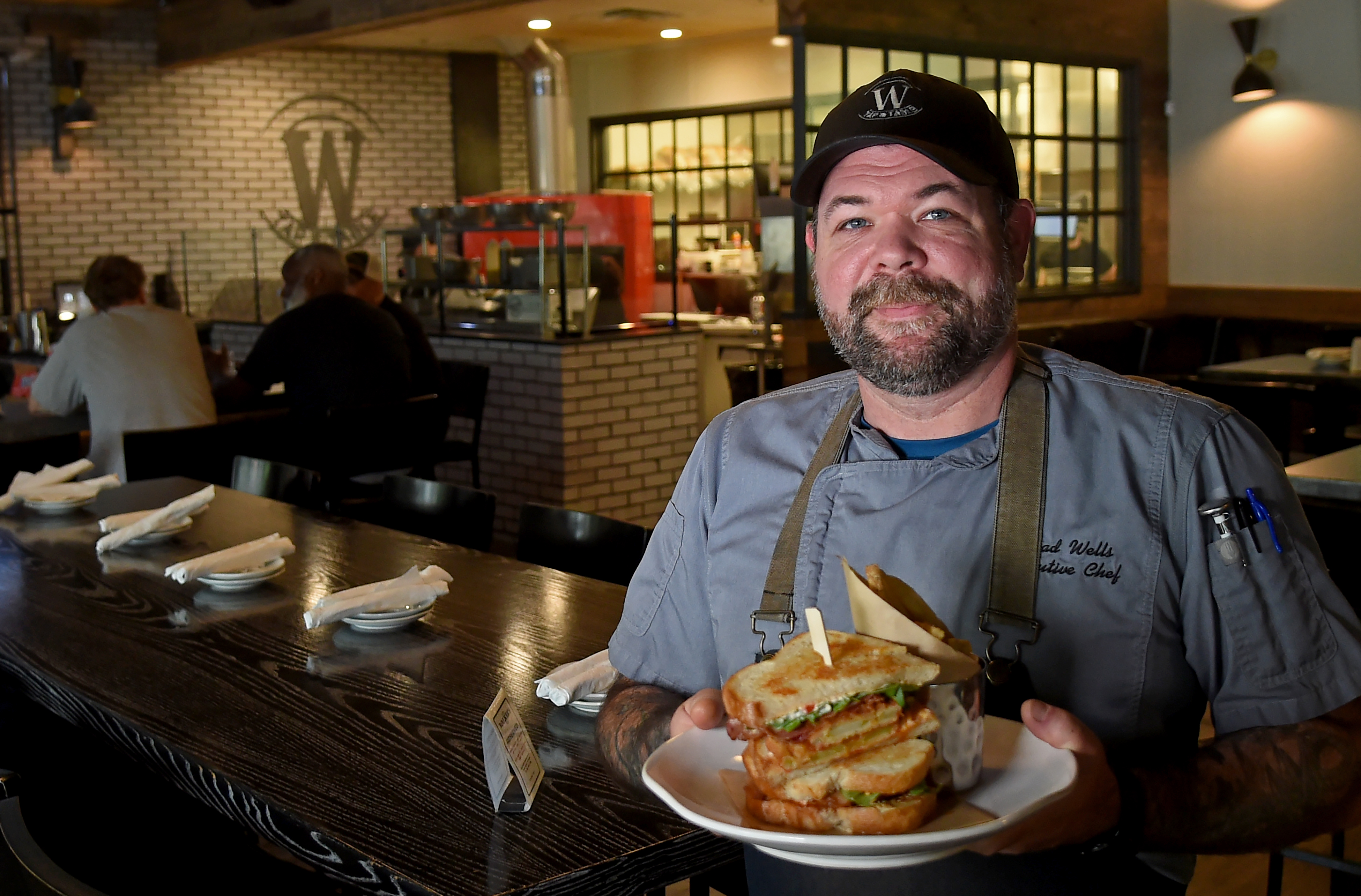 Chef Chad Wells, executive chef at Walker's Tap and Table, has been named best chef in Howard County. Here, he holds one of his creations: the Route 97 BLT with bacon, fried green tomatoes, habanero honey, arugula, and pimiento cheese on sourdough bread. (Barbara Haddock Taylor/Staff)
