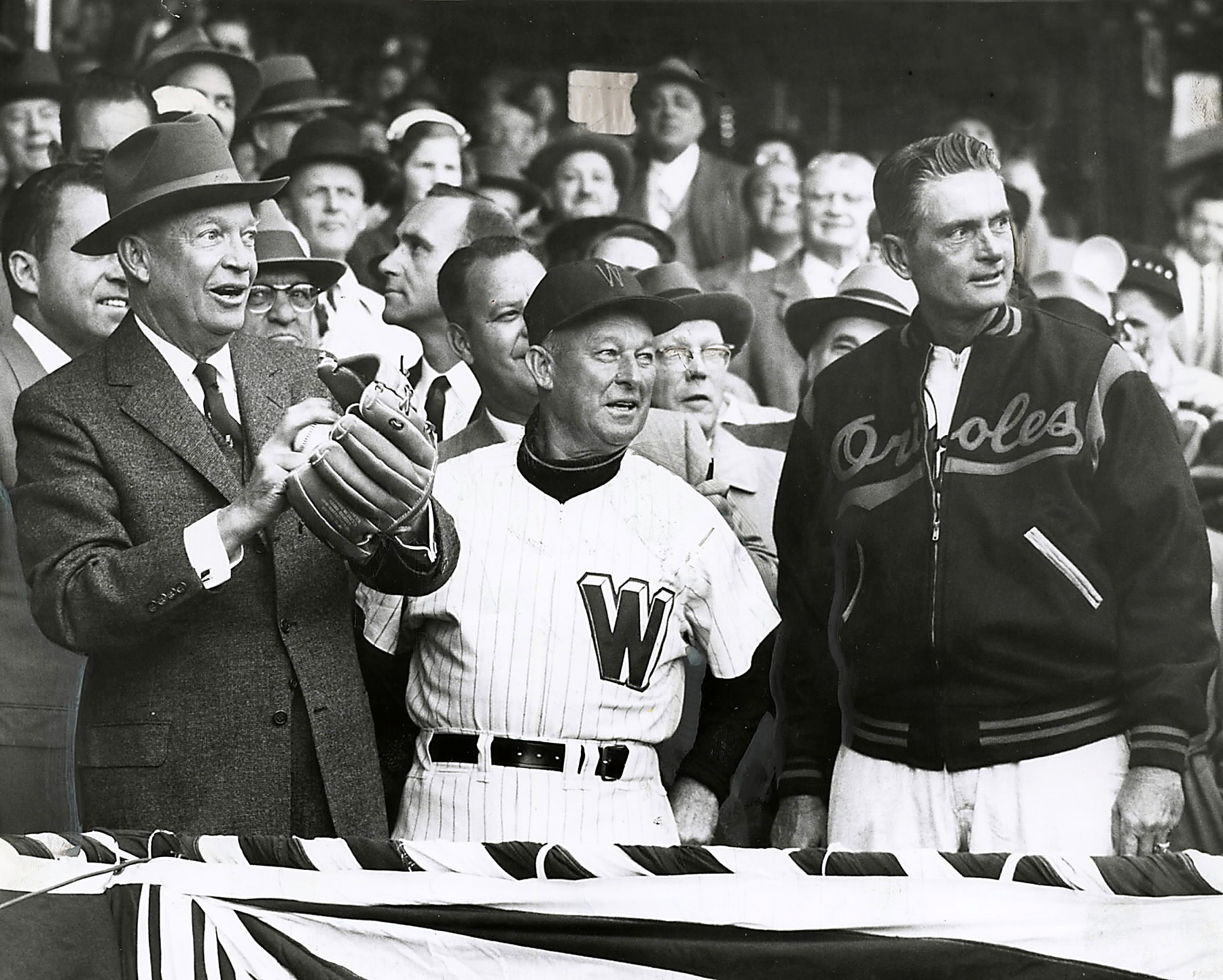 President Eisenhower throws out the first pitch at the 1957's opening day baseball game between the Baltimore Orioles and the Washington Senators as Managers Chuck Dressen (Washington) and Paul Richards (Orioles) watch.