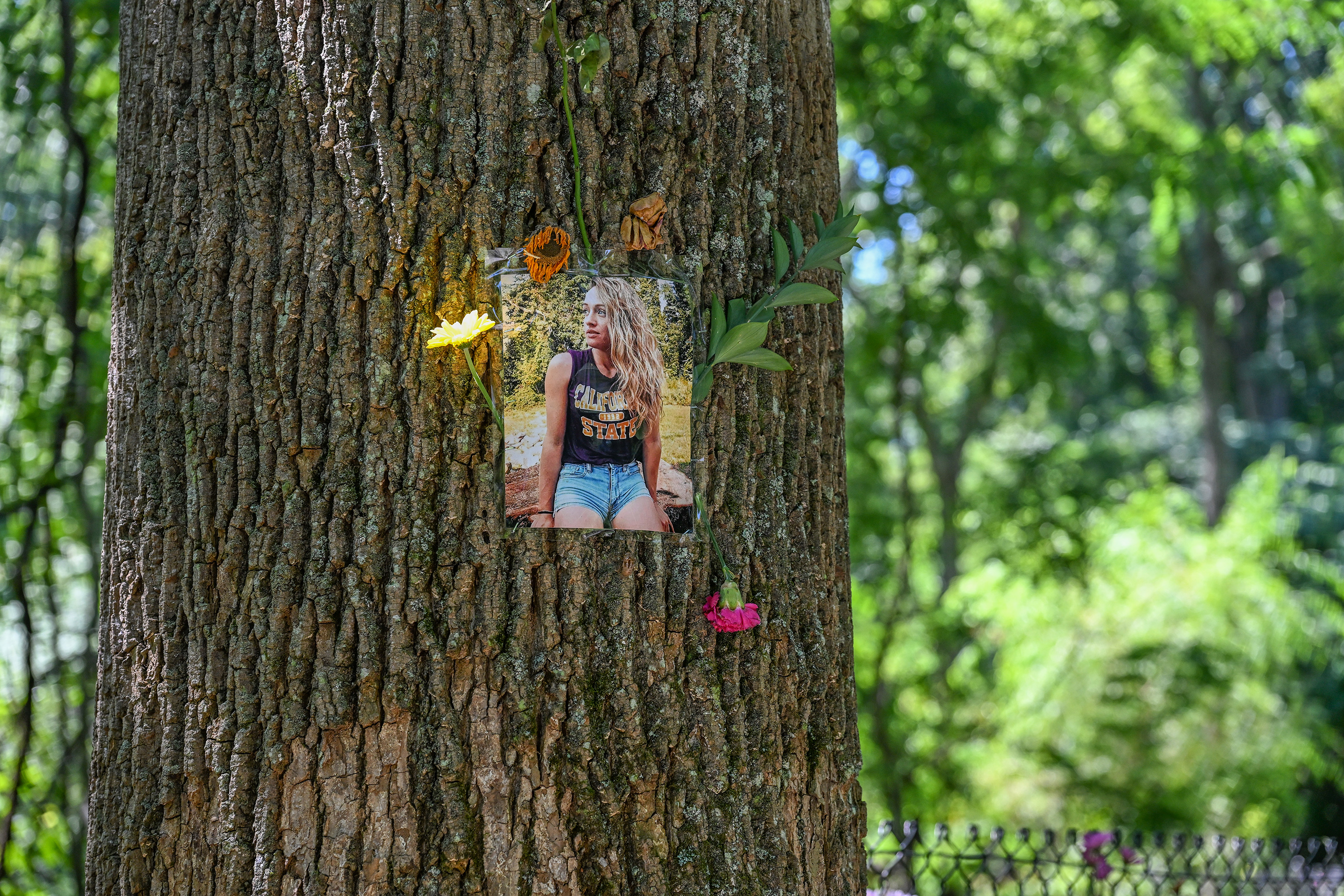 A photo of Rachel Morin is adorned with flowers along the Ma & Pa Trail during a memorial walk Saturday morning.