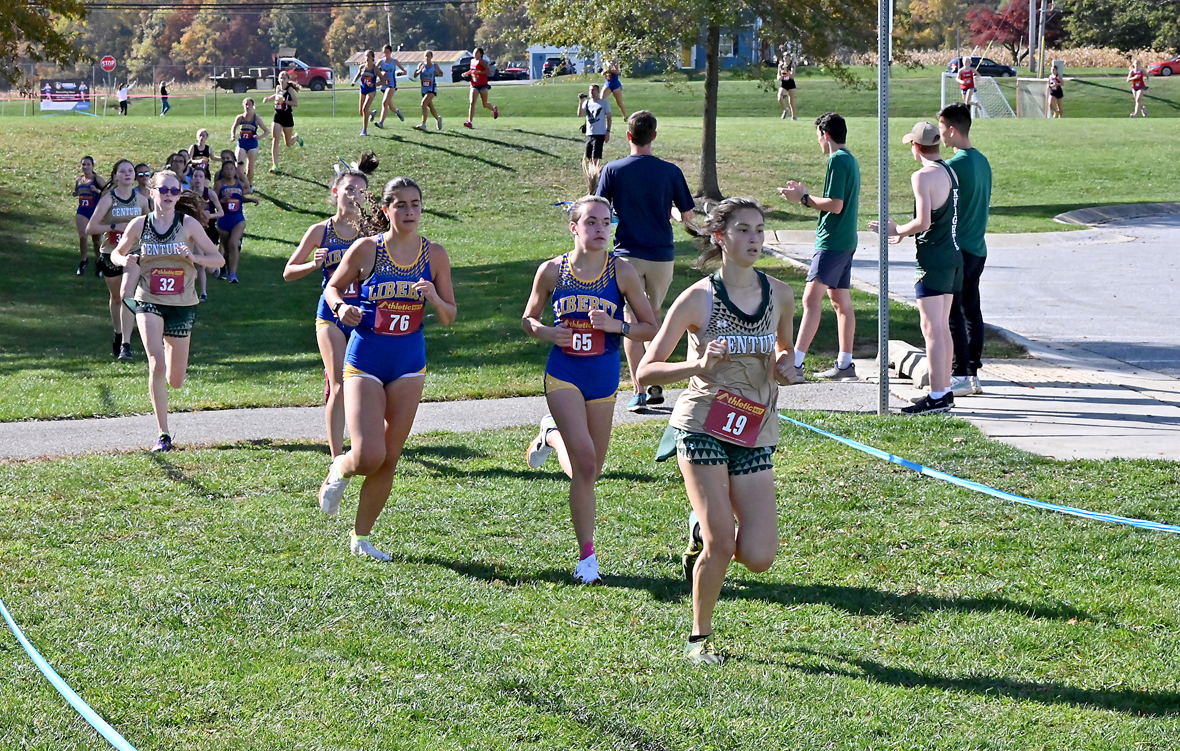 Runners come down a hill and make a turn early in the race at the Carroll county girls cross country championships, Thursday October 26, 2023 at Carroll Community College.