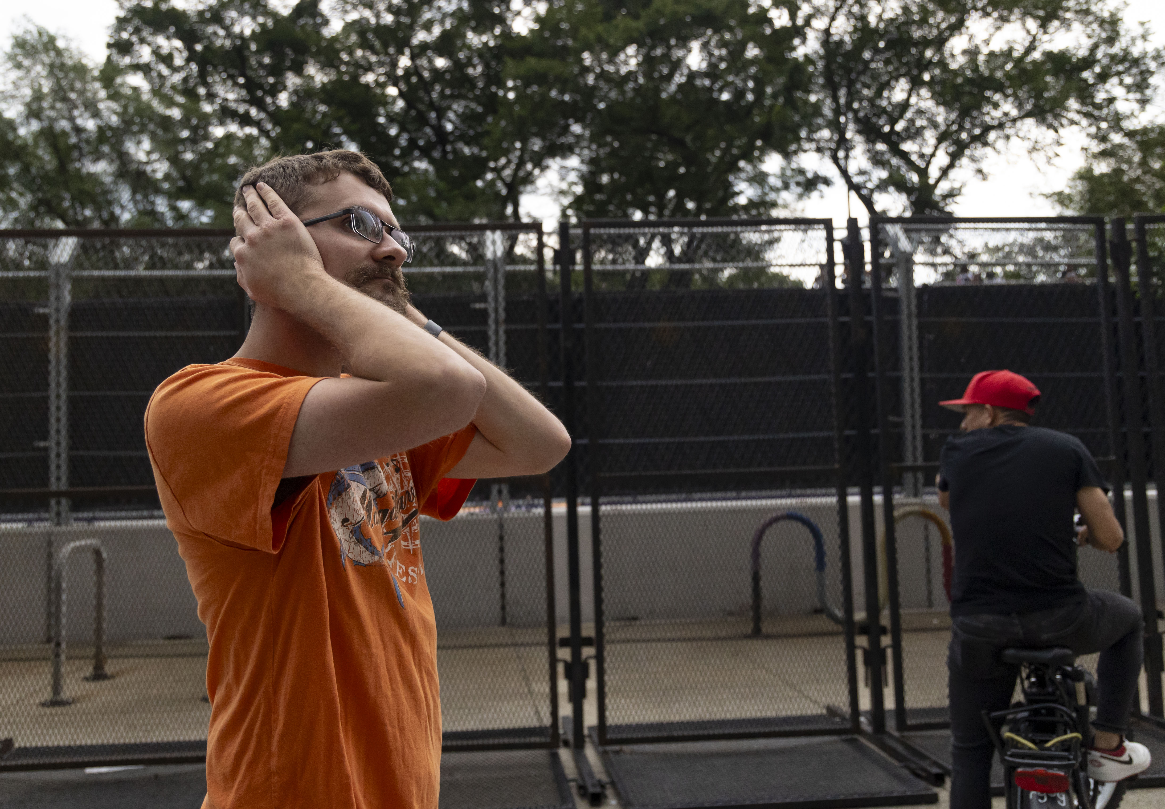 A person covers his ears as the cars race by across the barriers along South Michigan Avenue during the NASCAR Chicago Street Race on Sunday, July 7, 2024. (Brian Cassella/Chicago Tribune)