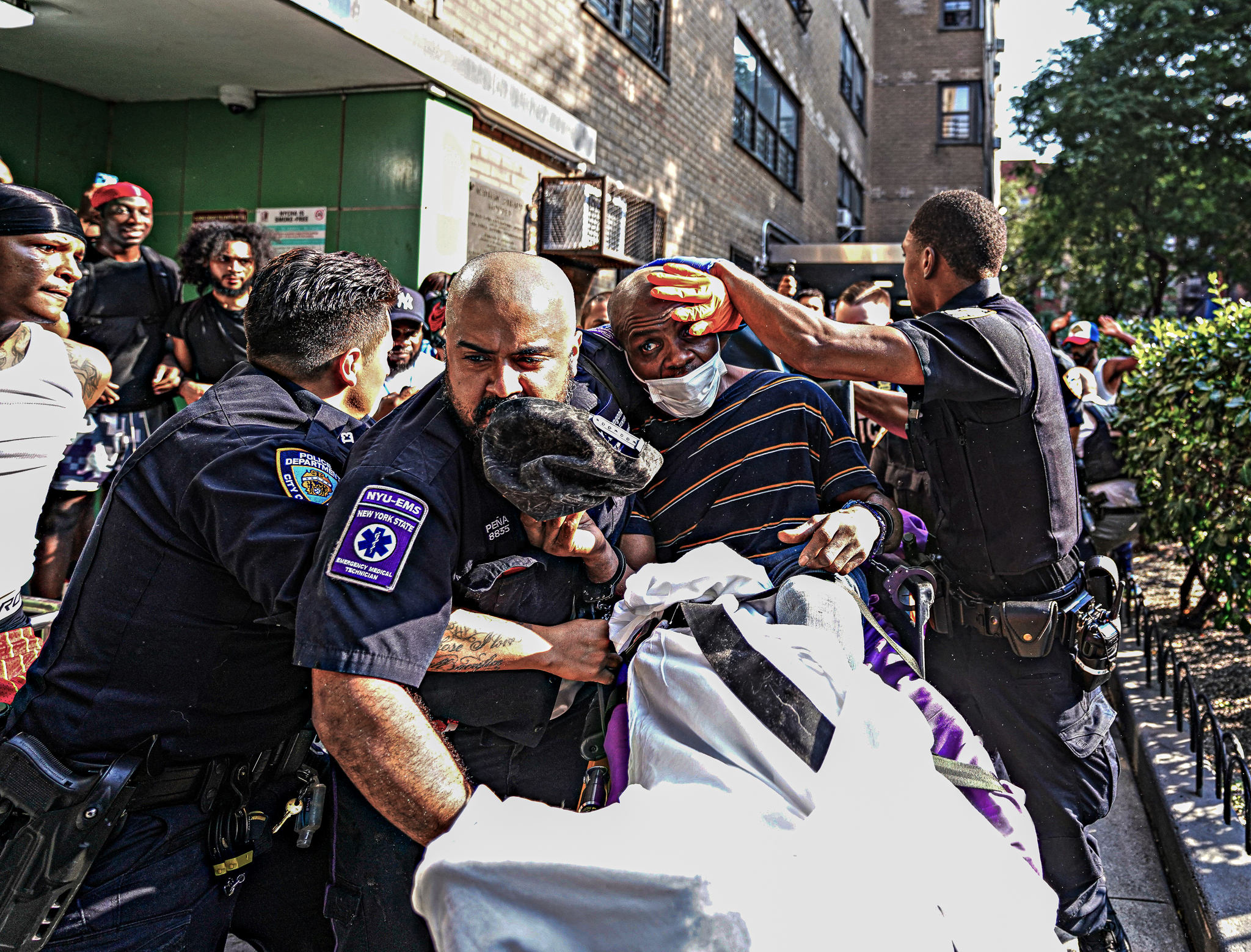 Police take suspect Chad Irish into custody on a stretcher as an angry mob tries to get at him Monday. (Photo by Dean Moses / amNewYork)