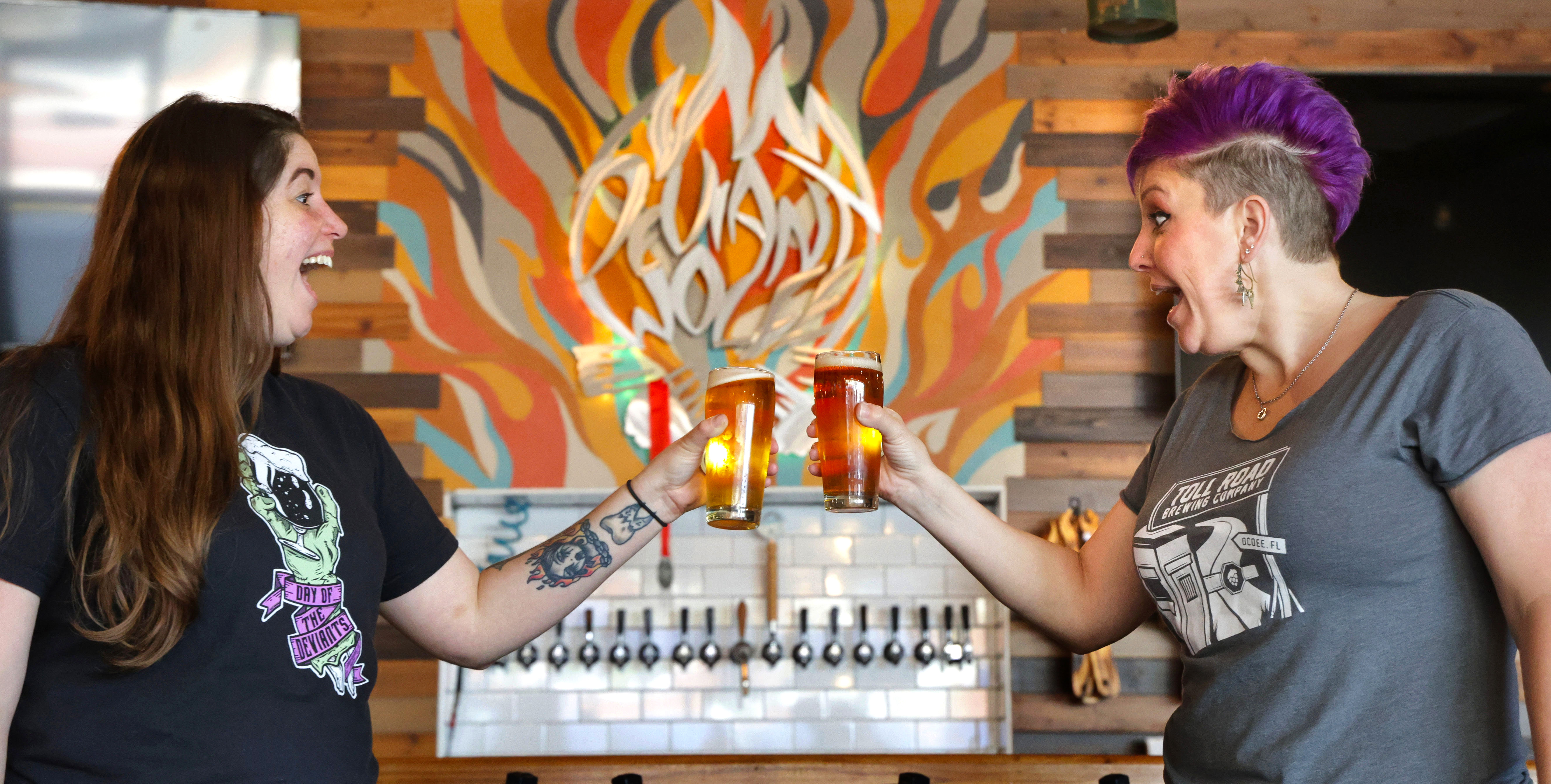 Heather Opheim of Deviant Wolfe Brewing, left, and Amanda Smythe from Tollroad Brewing raise a glass at Deviant Wolfe in downtown Sanford, Thursday, May 21, 2024. (Joe Burbank/Orlando Sentinel)