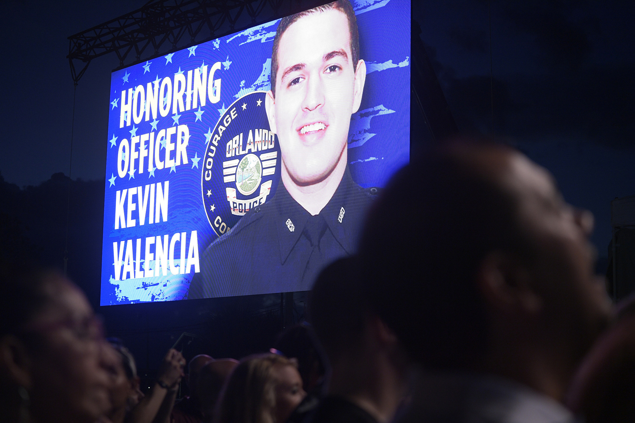A photo of Kevin Valencia is show on a video monitor during the free concert event, benefiting Orlando Police Department officer Kevin Valencia Saturday, June 1, 2019, in Orlando, Fla. (Phelan M. Ebenhack for the Orlando Sentinel)