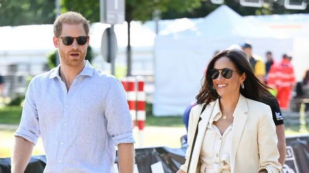 Prince Harry and Meghan Markle walking in shades, talking, looking confident, Meghan smiling