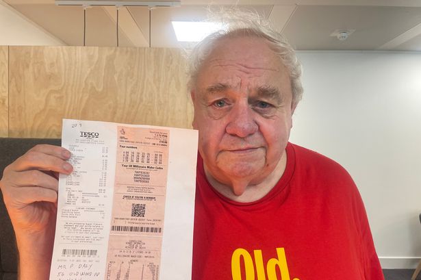 Pete Daly holding up his winning lottery ticket