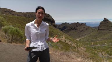 Laura Trott, dressed in a white shirt and holding an iPad, standing over a vast ravine in Tenerife near to where Jay Slater was found