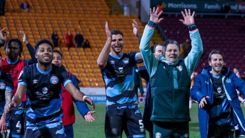 Steve Cotterill holds his arms in the air as he leads the Forest Green players in a round of applause towards their fans after the full-time whistle