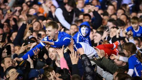 Paddy Lane of Portsmouth surfs the crowd that invaded the pitch at Fratton Park