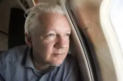 Julian Assange no avião, após deixar prisão no Reino Unido 