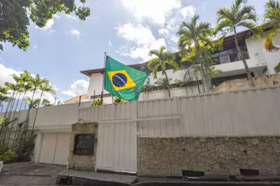 Bandeira do Brasil hasteada em casa branca de muro alto