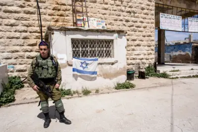 Um jovem soldado israelense guarda a entrada de um assentamento judeu em Hebron, na Cisjordânia