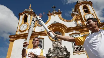 Atletas carregam a tocha olímpica em frente a uma igreja no Brasil em 2016