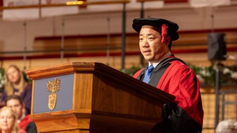 Aiyawatt ‘Top’ Srivaddhanaprabha speaking at a lectern at De Montfort Hall