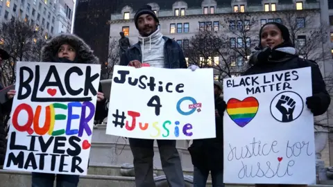 Reuters People holding signs saying: "Black queer lives matter" and "Justice 4 Jussie".