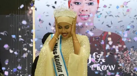 Shukri Mohamed Abdi A woman covering her ears and smiling as confetti is sprayed near her