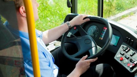 Driver in blue at the wheel of a public service bus